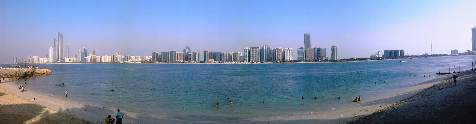Palm-lined Corniche promenade and beach with the Abu Dhabi skyline, United Arab Emirates
