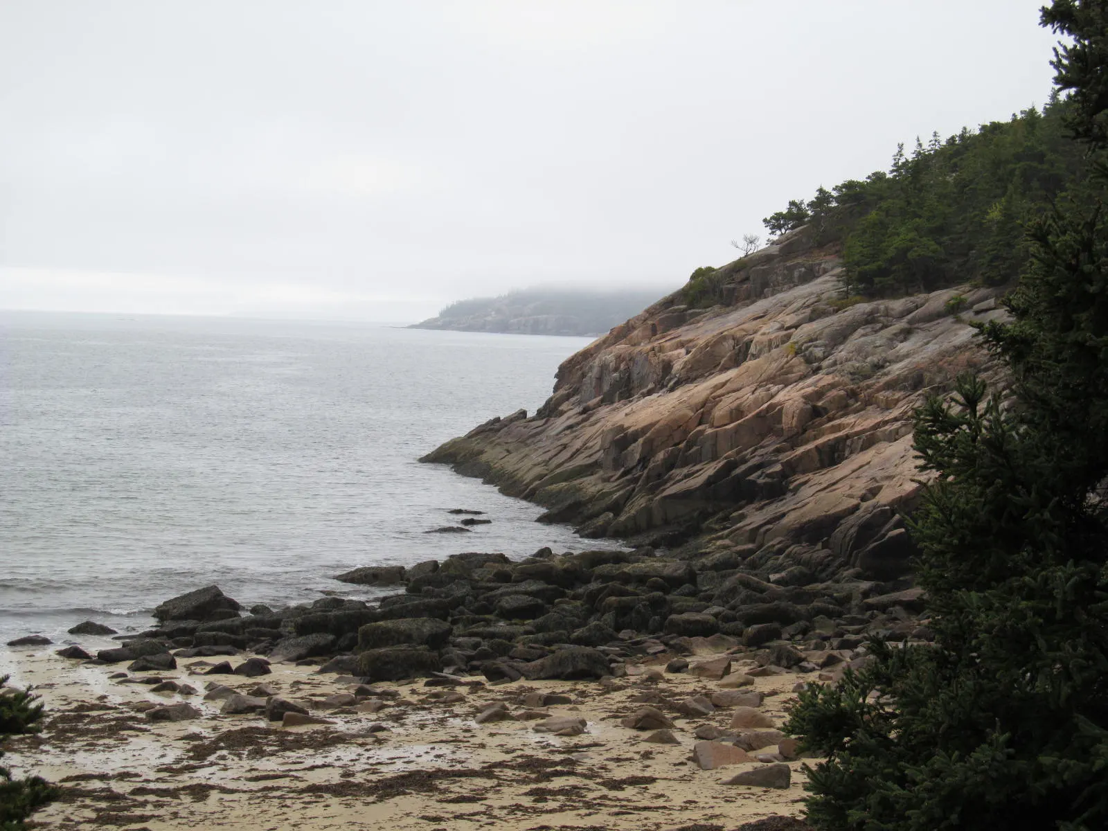 Curving pale sand beach between granite headlands with the Beehive behind, Acadia National Park, Maine