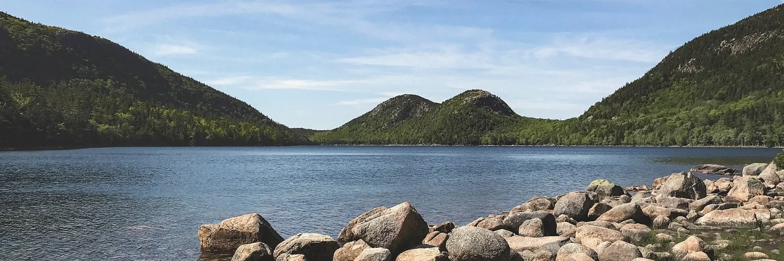 Clear water of Jordan Pond with the twin rounded Bubbles mountains at the far end, Acadia National Park, Maine