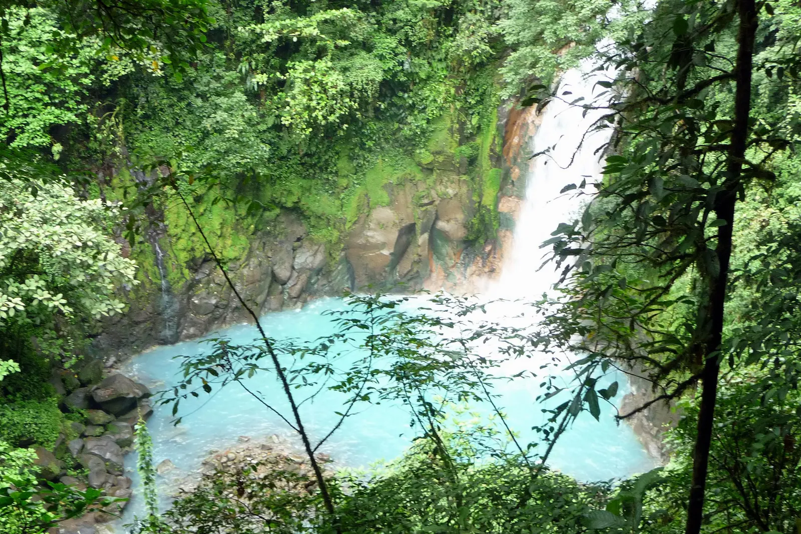 A waterfall pouring into a vivid sky-blue pool in Tenorio Volcano National Park, Arenal, Costa Rica