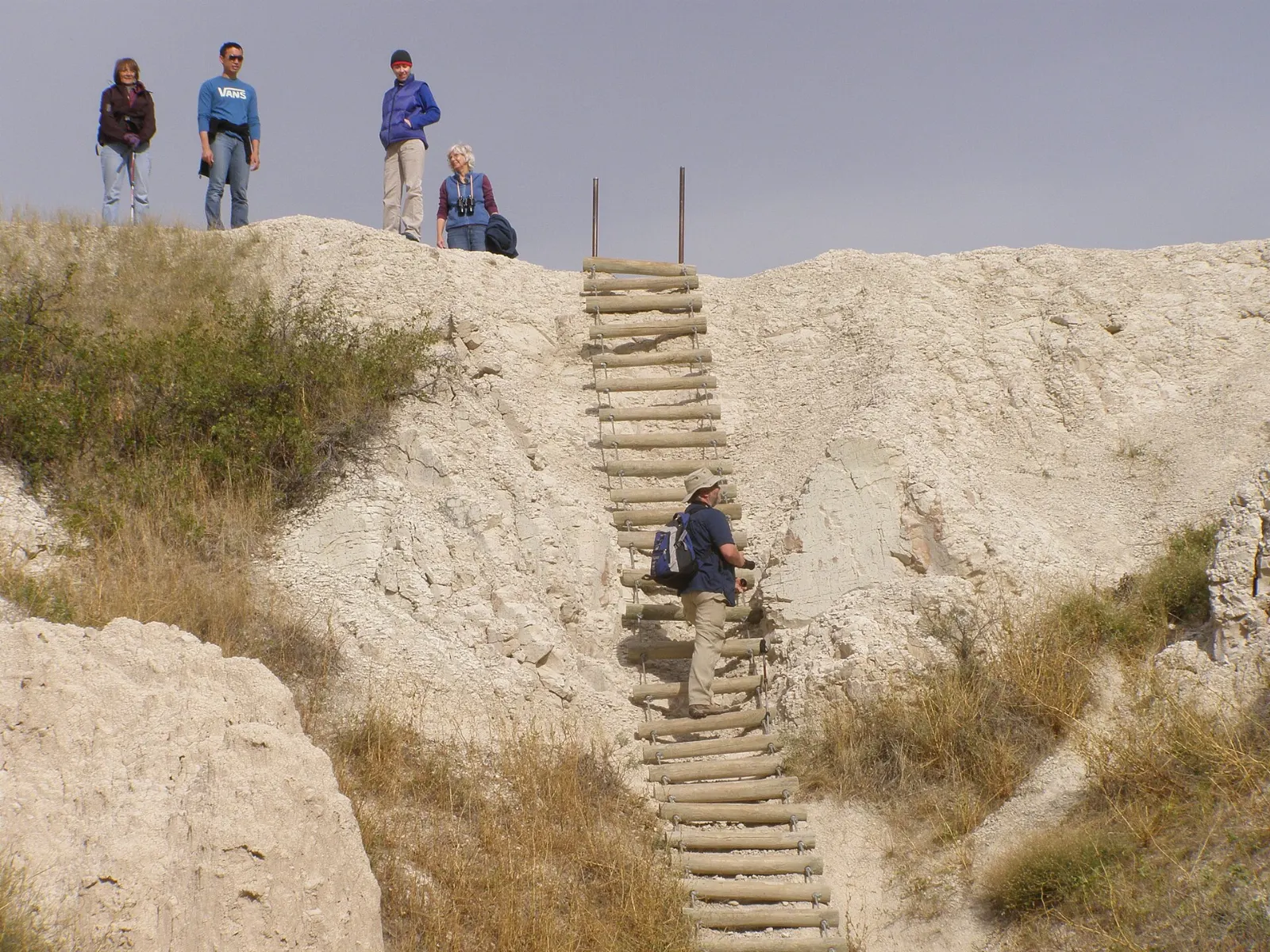 Hikers climbing a steep ladder on the Notch Trail, Badlands National Park, South Dakota