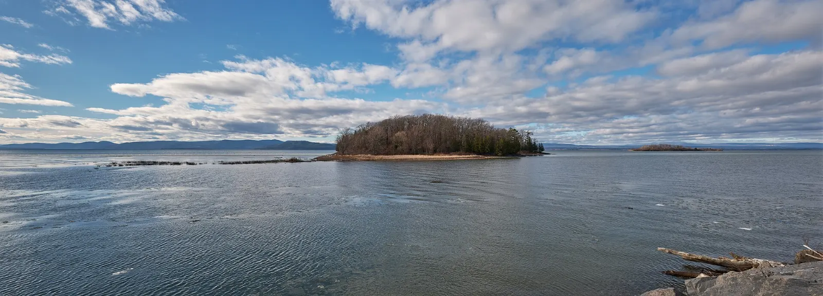 A narrow gravel causeway path stretching across the blue water of Lake Champlain, Burlington, Vermont