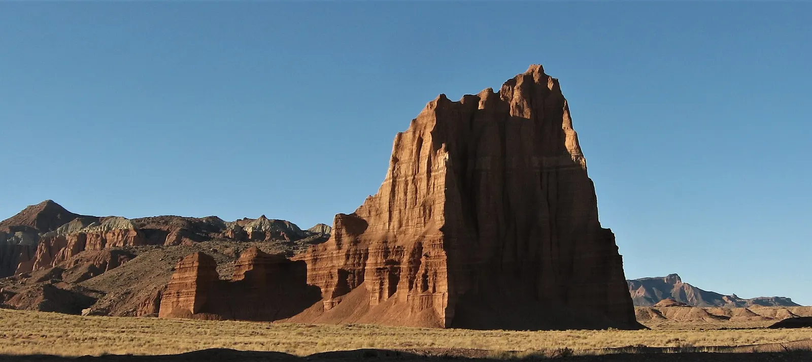 A tall eroded sandstone monolith rising from a flat desert valley, Capitol Reef National Park, Utah