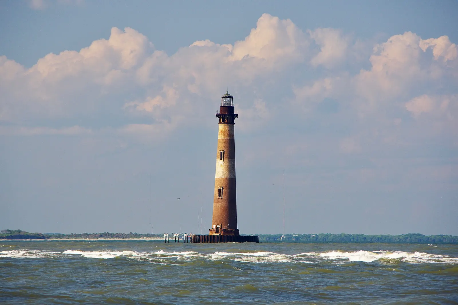 Lighthouse standing offshore in the surf near a beach, Charleston, South Carolina