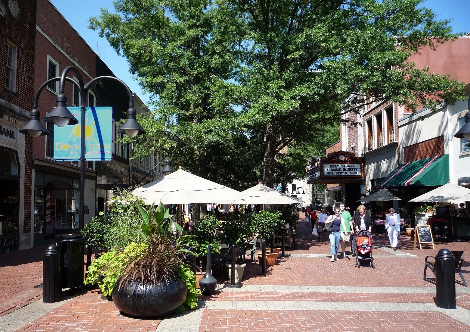 Brick pedestrian street lined with trees, shops and outdoor dining on the Charlottesville Downtown Mall, Virginia