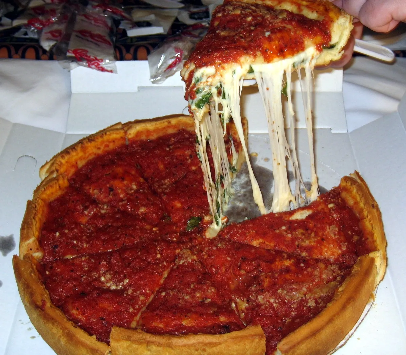 A slice of Chicago-style deep-dish pizza with a tall crust and chunky tomato sauce on top, Illinois