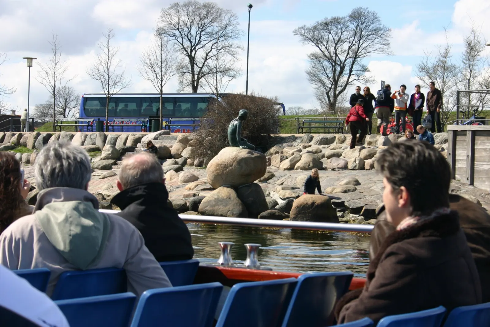 A small bronze statue of a mermaid sitting on a rock by the water, Copenhagen, Denmark