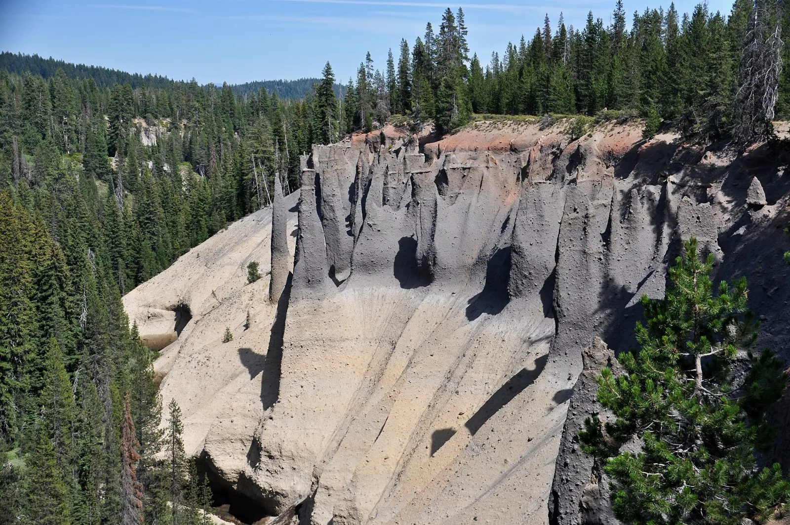 Tall pointed spires of volcanic rock rising from a forested canyon wall, Crater Lake National Park, Oregon