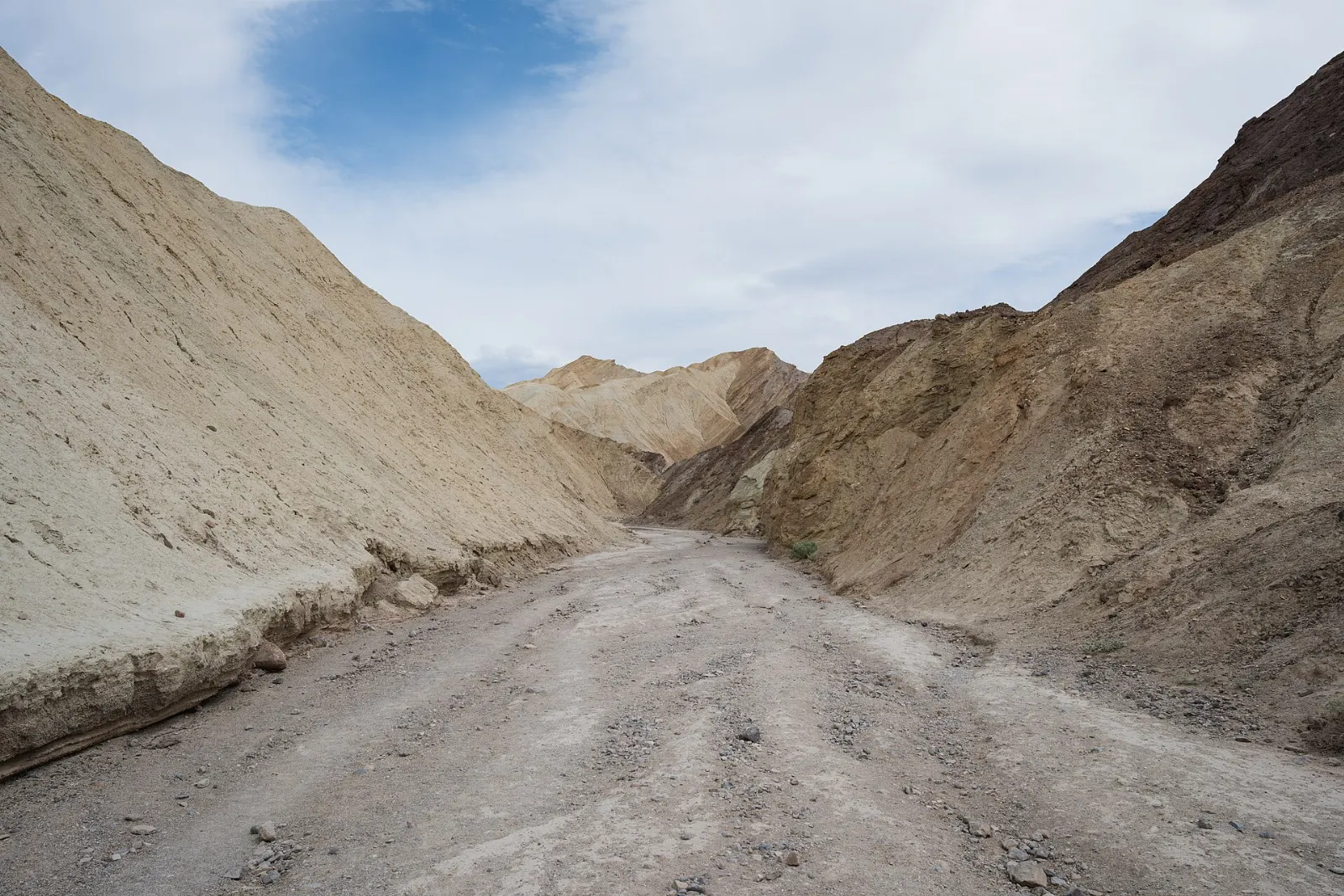 A narrow trail winding through golden canyon walls toward a red cliff, Death Valley National Park, California