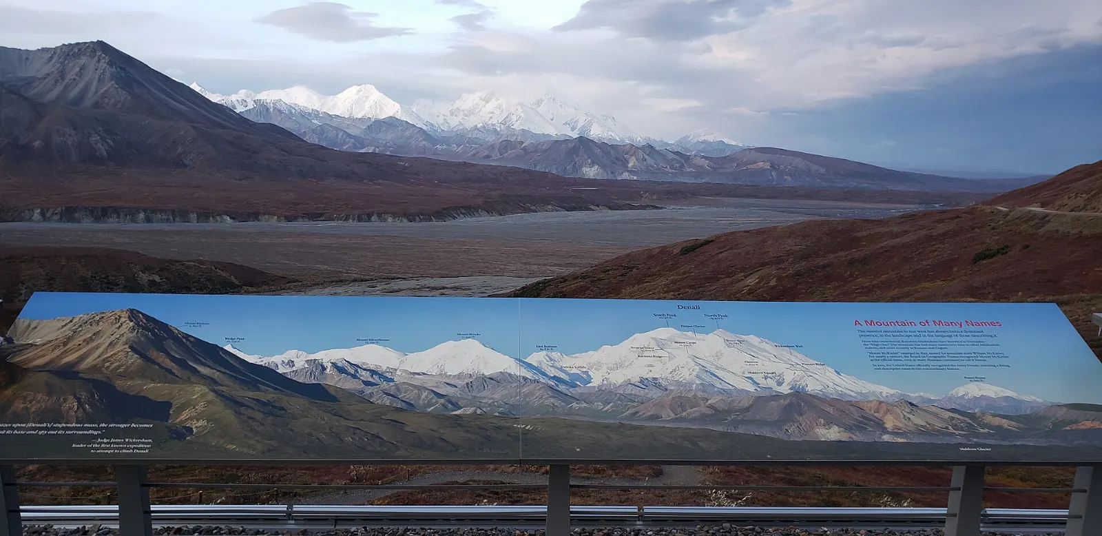 A low visitor center built into a hillside with tundra and mountains beyond, Denali National Park, Alaska