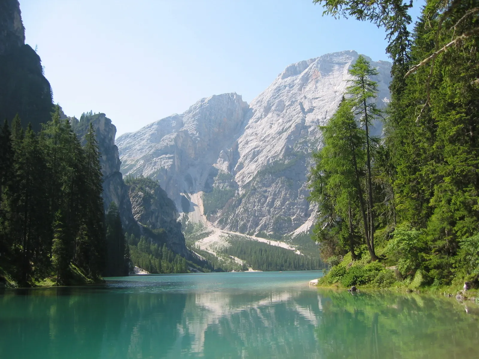 Wooden rowing boats on an emerald lake beneath a steep limestone peak, Dolomites, Italy