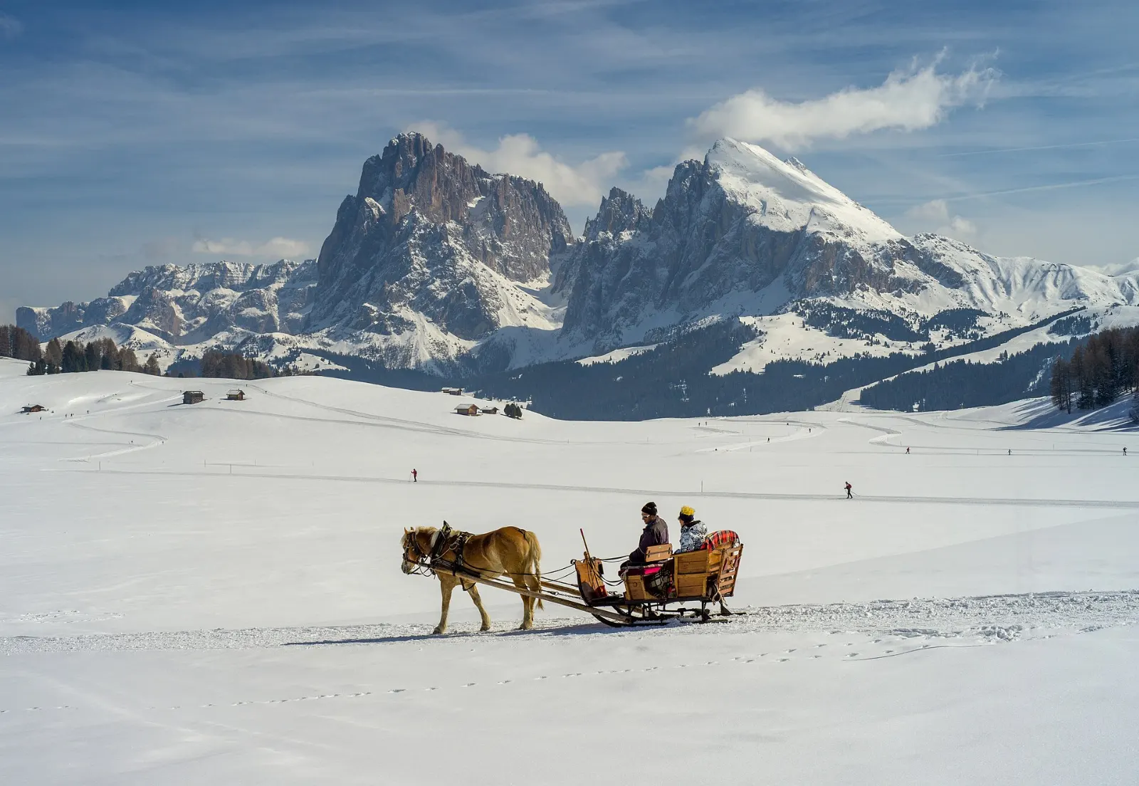 Rolling green pastures with wooden huts and a massive rock peak beyond, Dolomites, Italy
