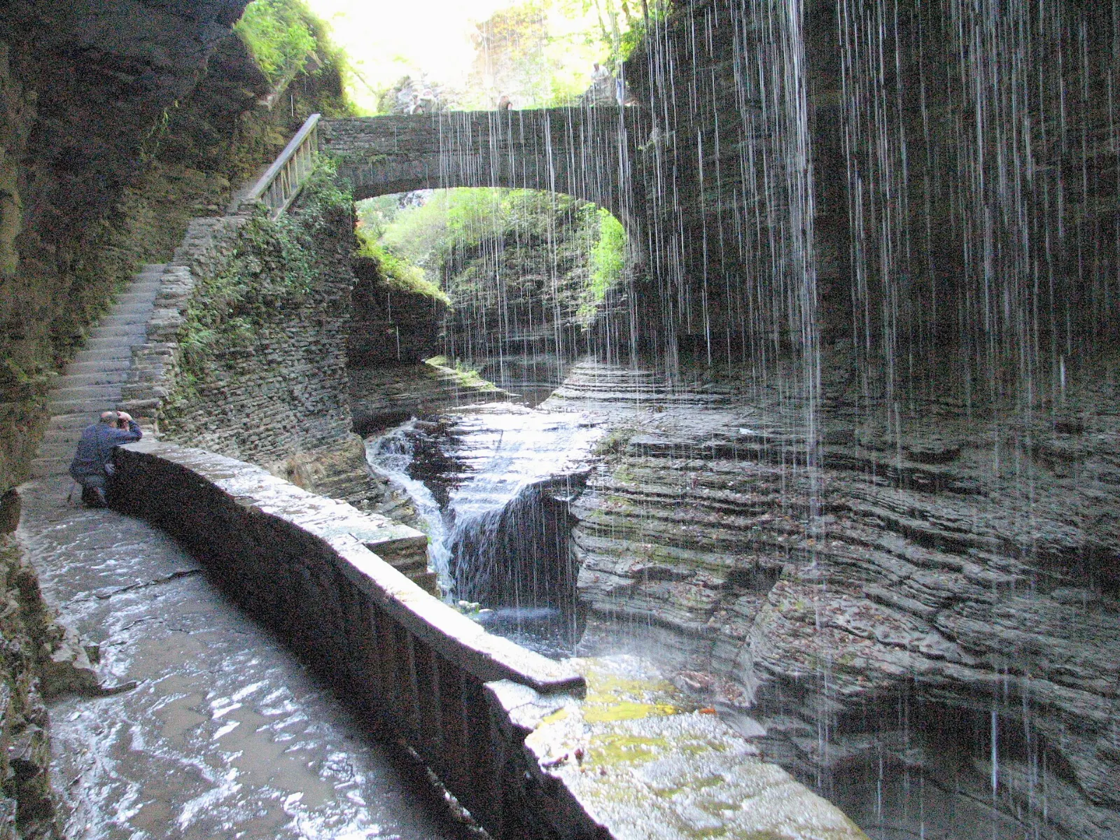 The Gorge Trail passing behind a waterfall in the stone-walled gorge at Watkins Glen, Finger Lakes, New York