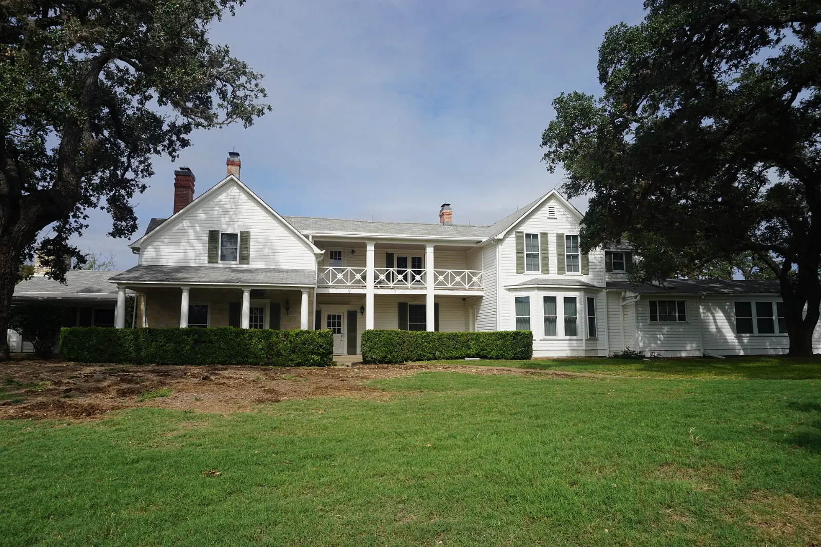 White ranch house under large oak trees on the LBJ Ranch near Stonewall, Fredericksburg, Texas