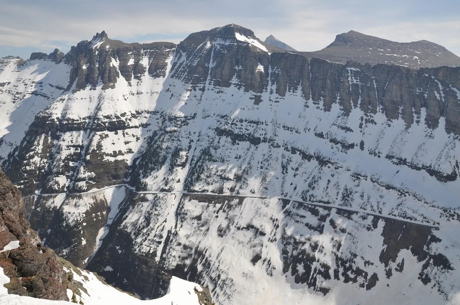 The narrow Going-to-the-Sun Road carved into a cliff face below jagged peaks, Glacier National Park, Montana