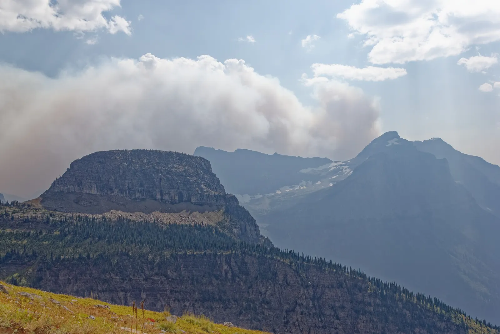 Hikers on a narrow ledge trail high above a deep valley on the Highline Trail, Glacier National Park, Montana