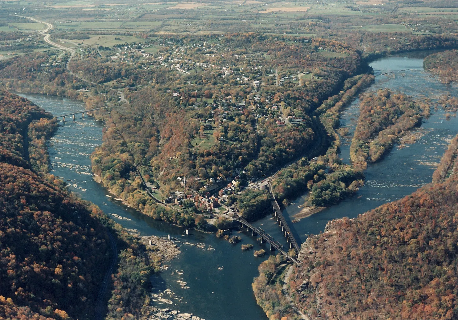 Rivers meeting below wooded cliffs at the Point in Harpers Ferry, with railroad bridges crossing the Potomac, West Virginia