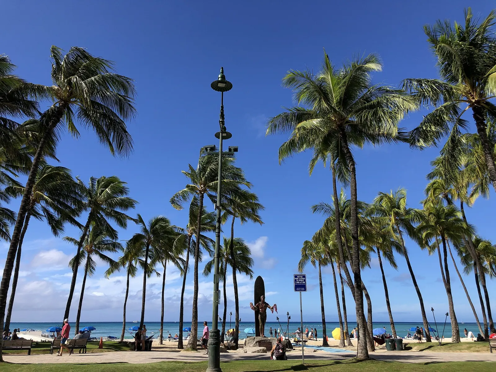 Bronze statue of Duke Kahanamoku with outstretched arms draped in flower lei, Honolulu, Hawaii