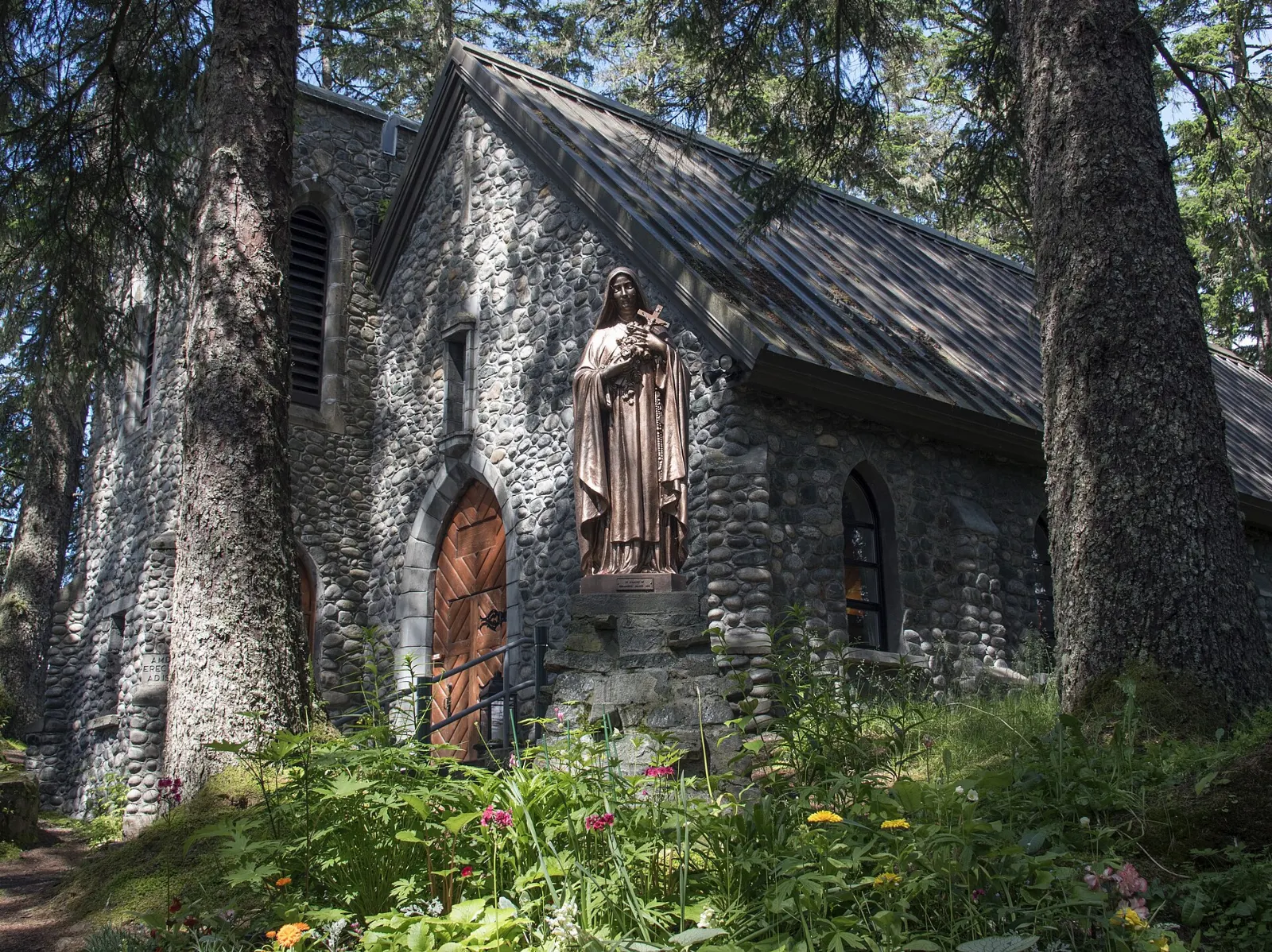 A small stone chapel on a wooded islet joined to the shore by a causeway, Juneau, Alaska
