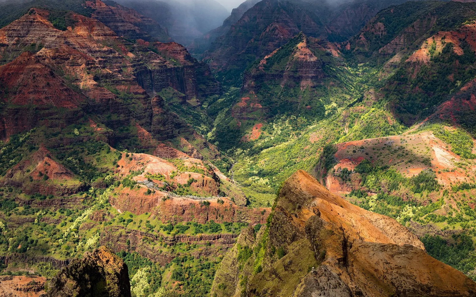Layered red and green walls of Waimea Canyon under scattered clouds, Kauai, Hawaii