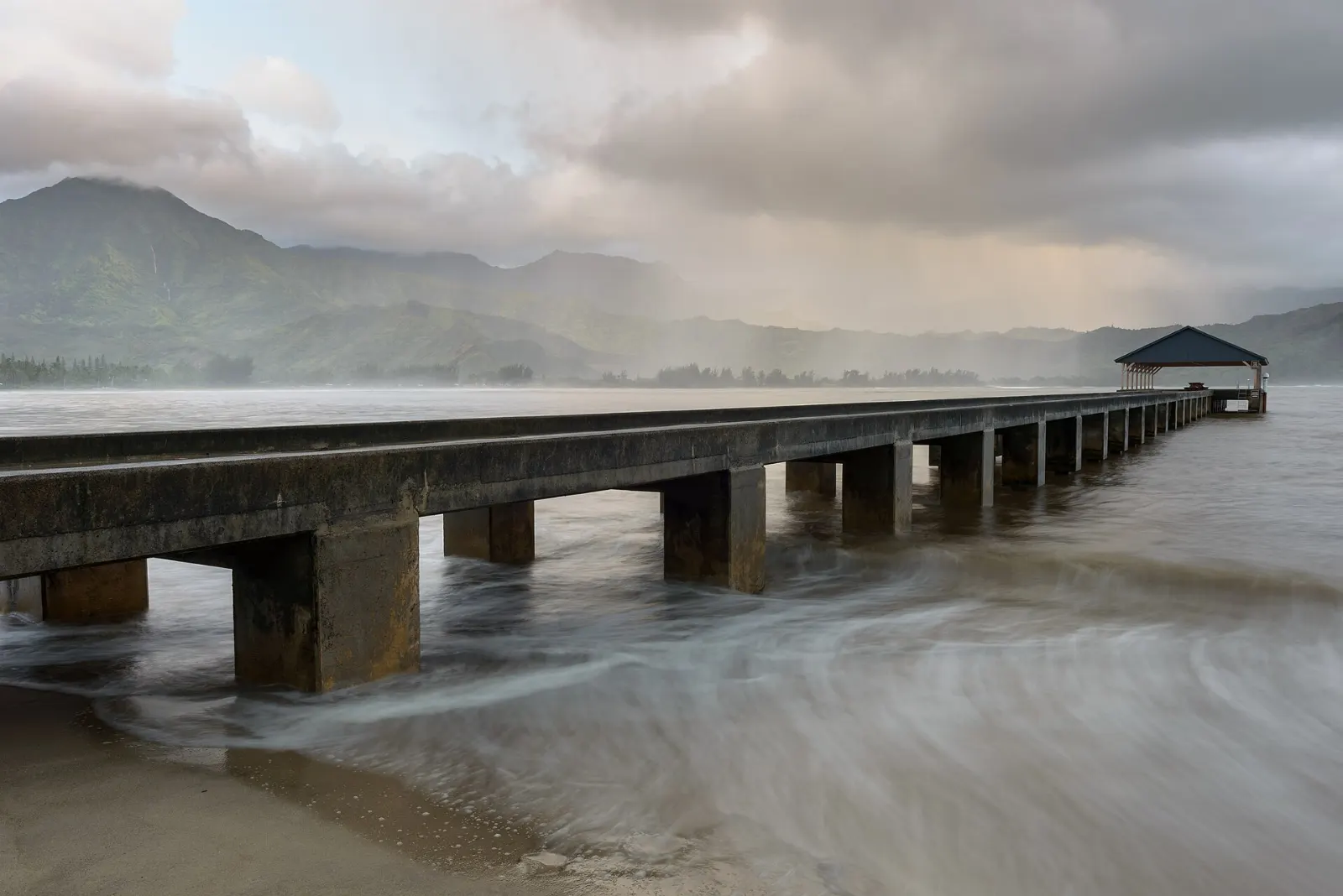Hanalei Pier extending into a wide crescent bay backed by green mountains, Kauai, Hawaii