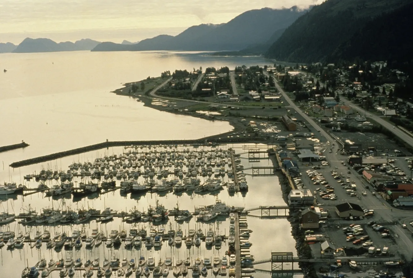 Fishing and tour boats moored in a harbor beneath snowy mountains, Kenai Fjords National Park, Alaska