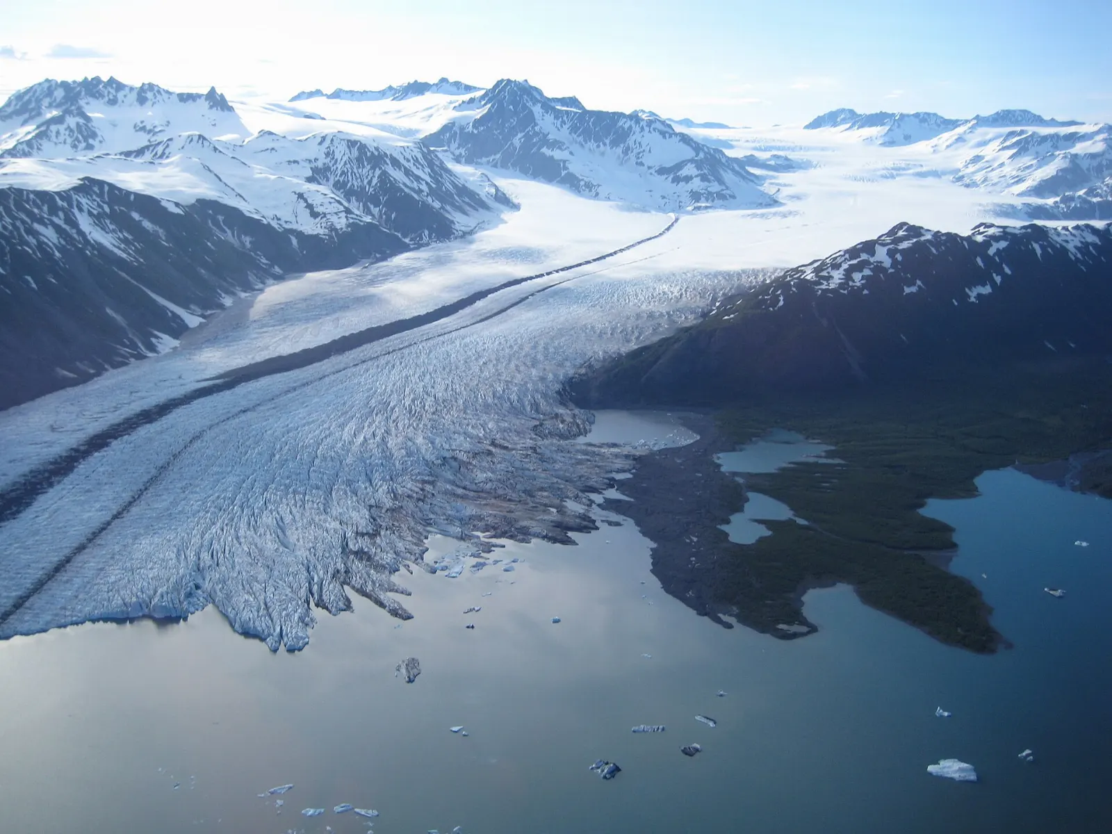 A wide glacier ending in an iceberg-filled lagoon near the coast, Kenai Fjords National Park, Alaska