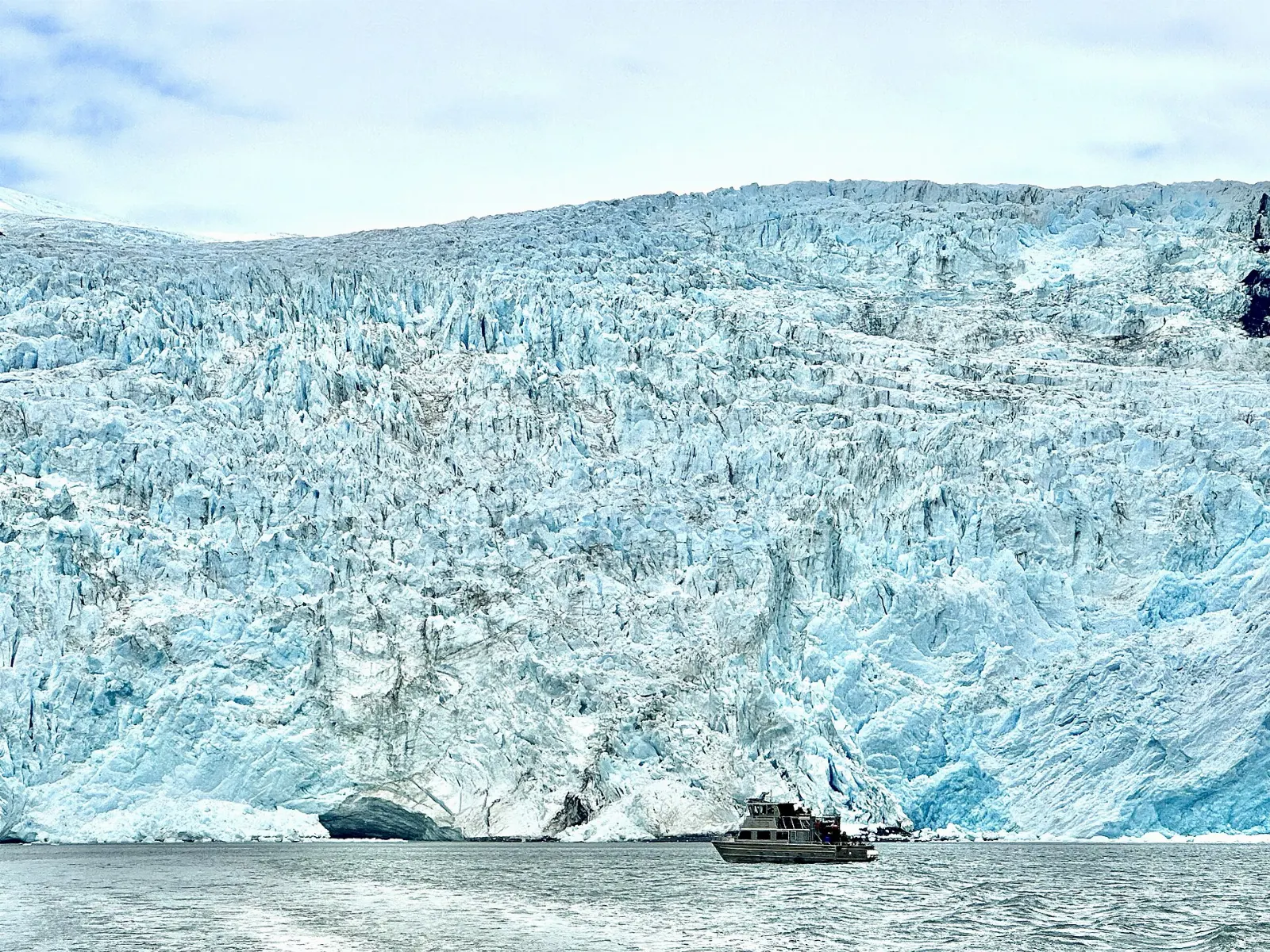 A blue ice face of a glacier calving into a narrow arm of the sea, Kenai Fjords National Park, Alaska