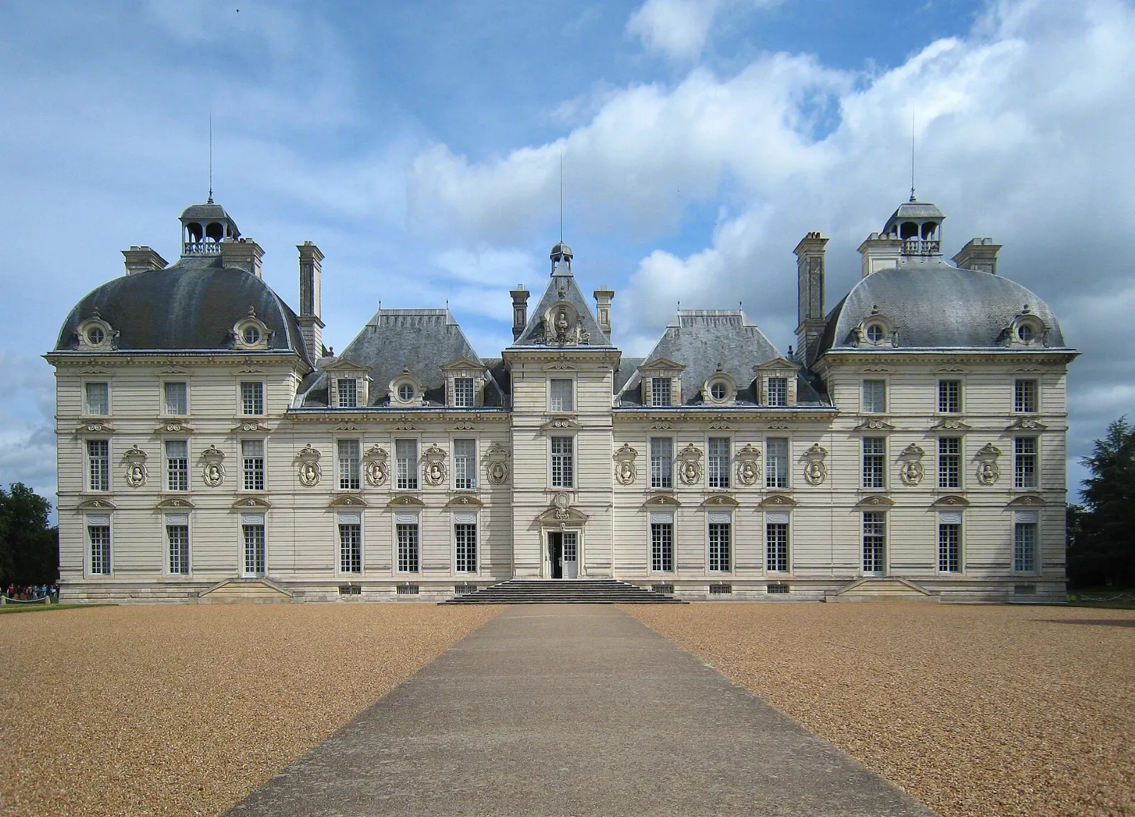The symmetrical pale stone facade of the Château de Cheverny behind a wide lawn, Loire Valley, France
