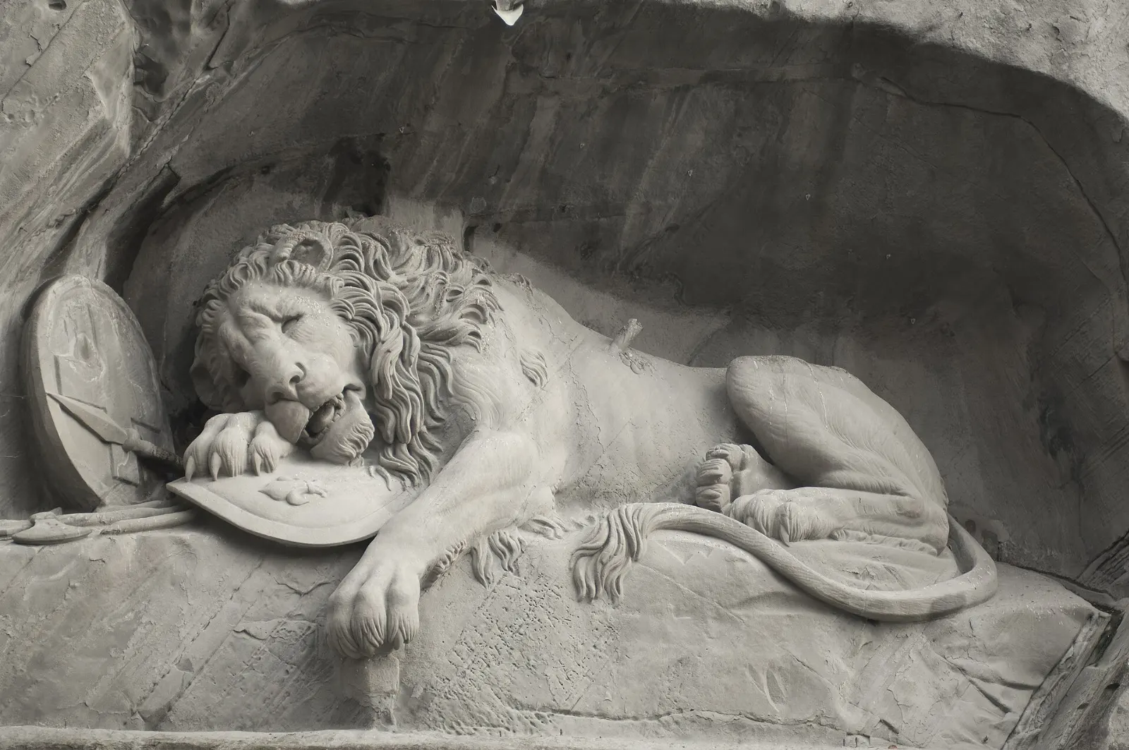 Carved dying lion in a rock face above a small pond at the Lion Monument, Lucerne, Switzerland
