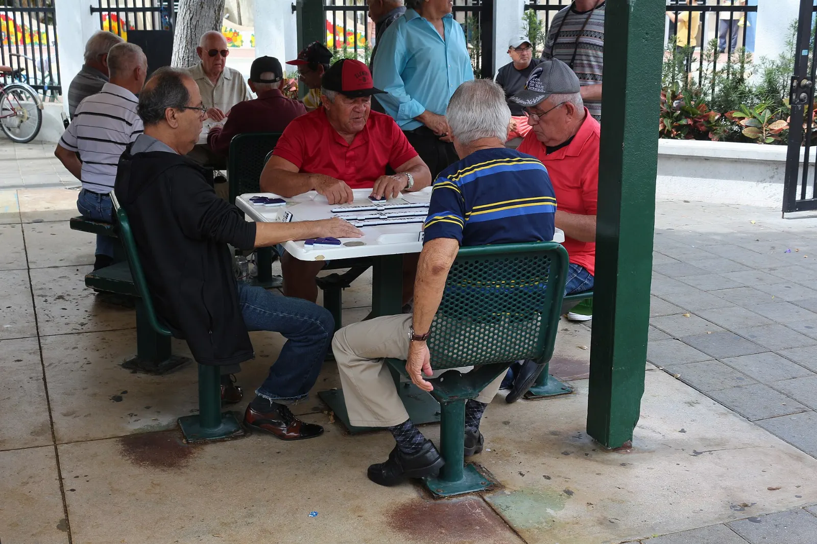 Men playing dominoes at tables in Máximo Gómez Park, Miami, Florida