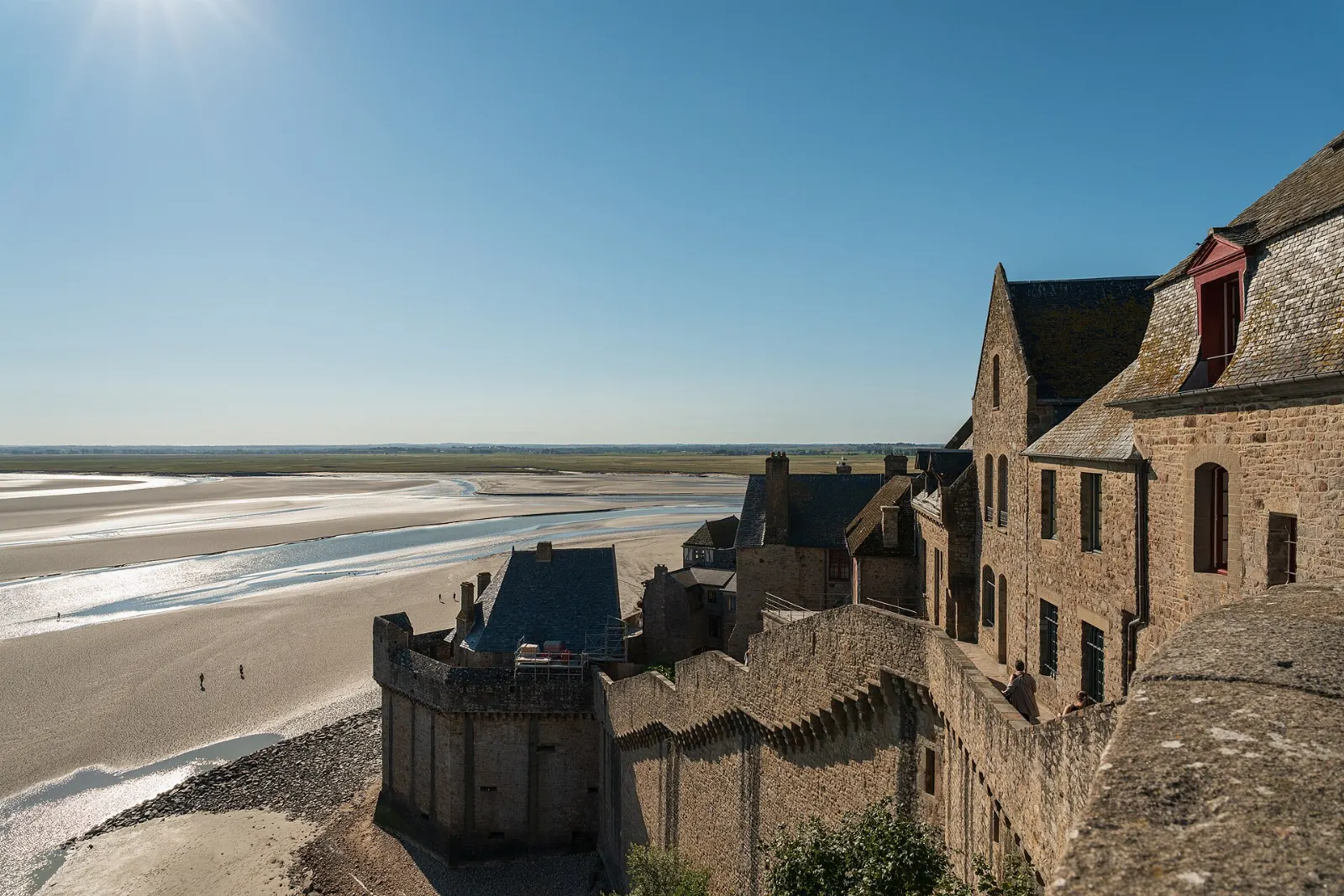 Stone ramparts and towers of Mont-Saint-Michel overlooking the sands of the bay, France