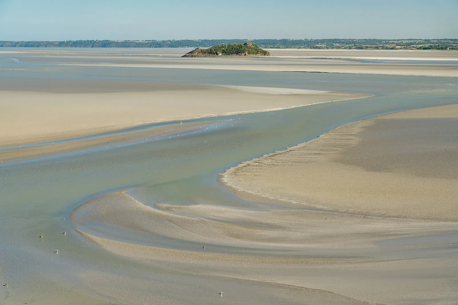 The small rocky islet of Tombelaine on the tidal flats of the bay, Mont-Saint-Michel, France