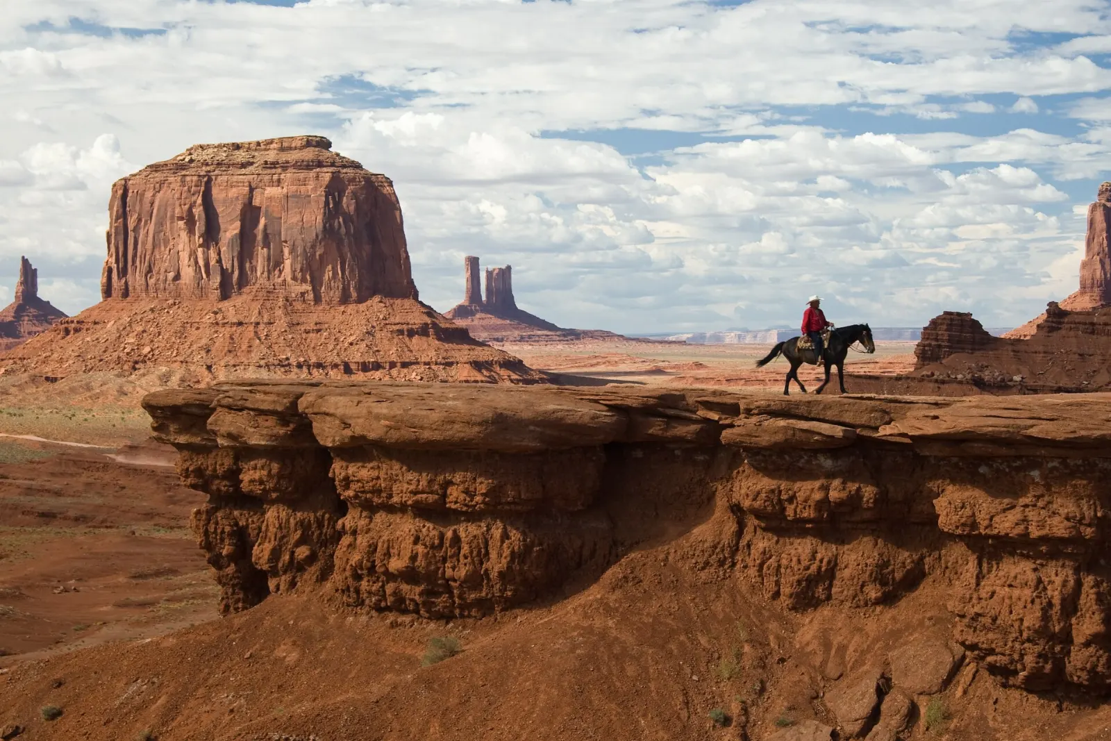 Rock ledge overlooking sweeping buttes and red sand in Monument Valley