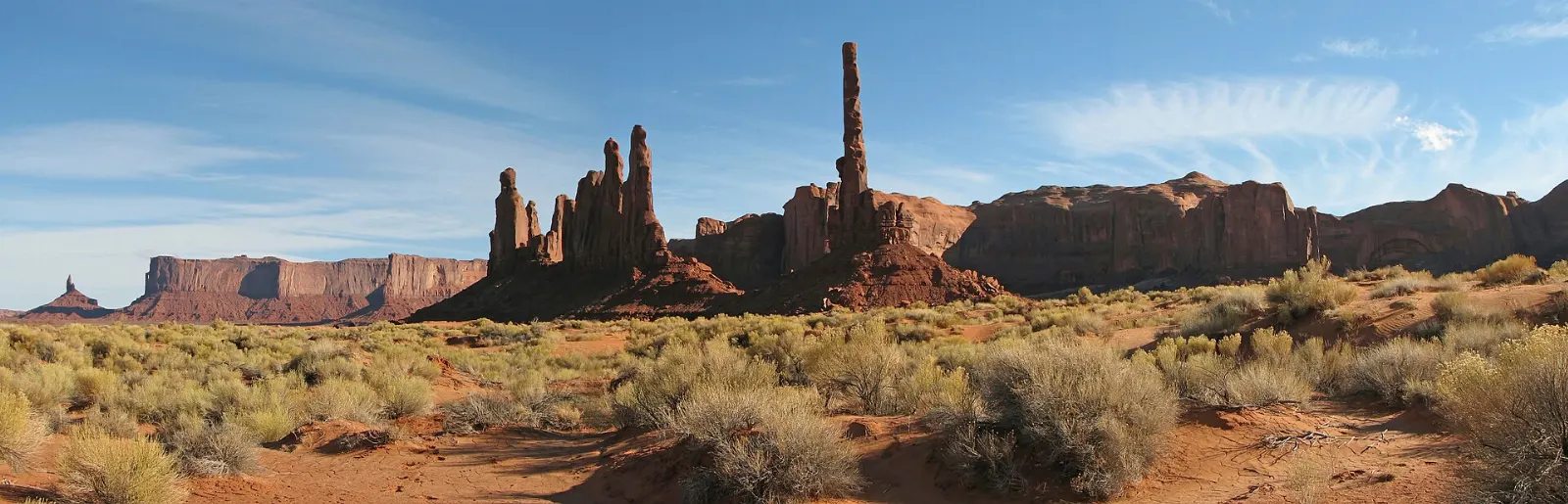 A tall, thin rock spire beside a cluster of smaller spires above sand dunes, Monument Valley, Arizona and Utah