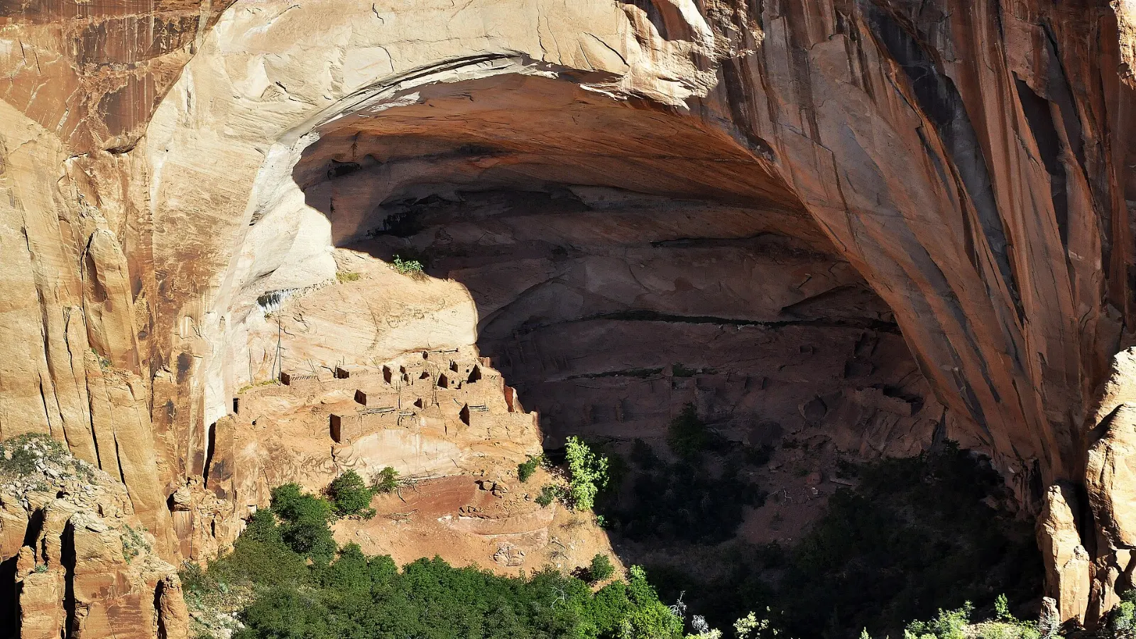Ancient stone cliff dwelling tucked inside a huge alcove in a red canyon wall, Monument Valley, Arizona and Utah