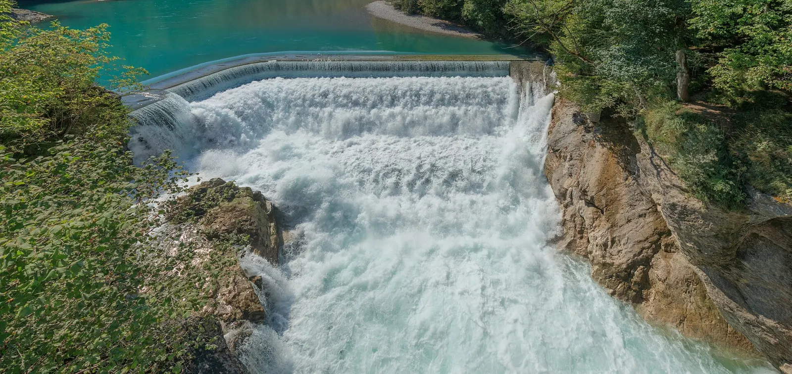 Turquoise water of the Lech pouring over the weir at the Lechfall below a footbridge, Neuschwanstein and Füssen, Germany