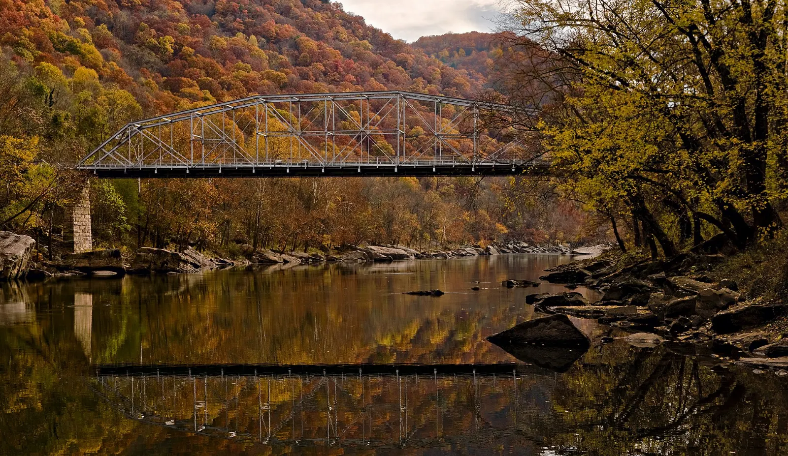 A small low bridge over the river with the high arch bridge towering above, New River Gorge National Park, West Virginia