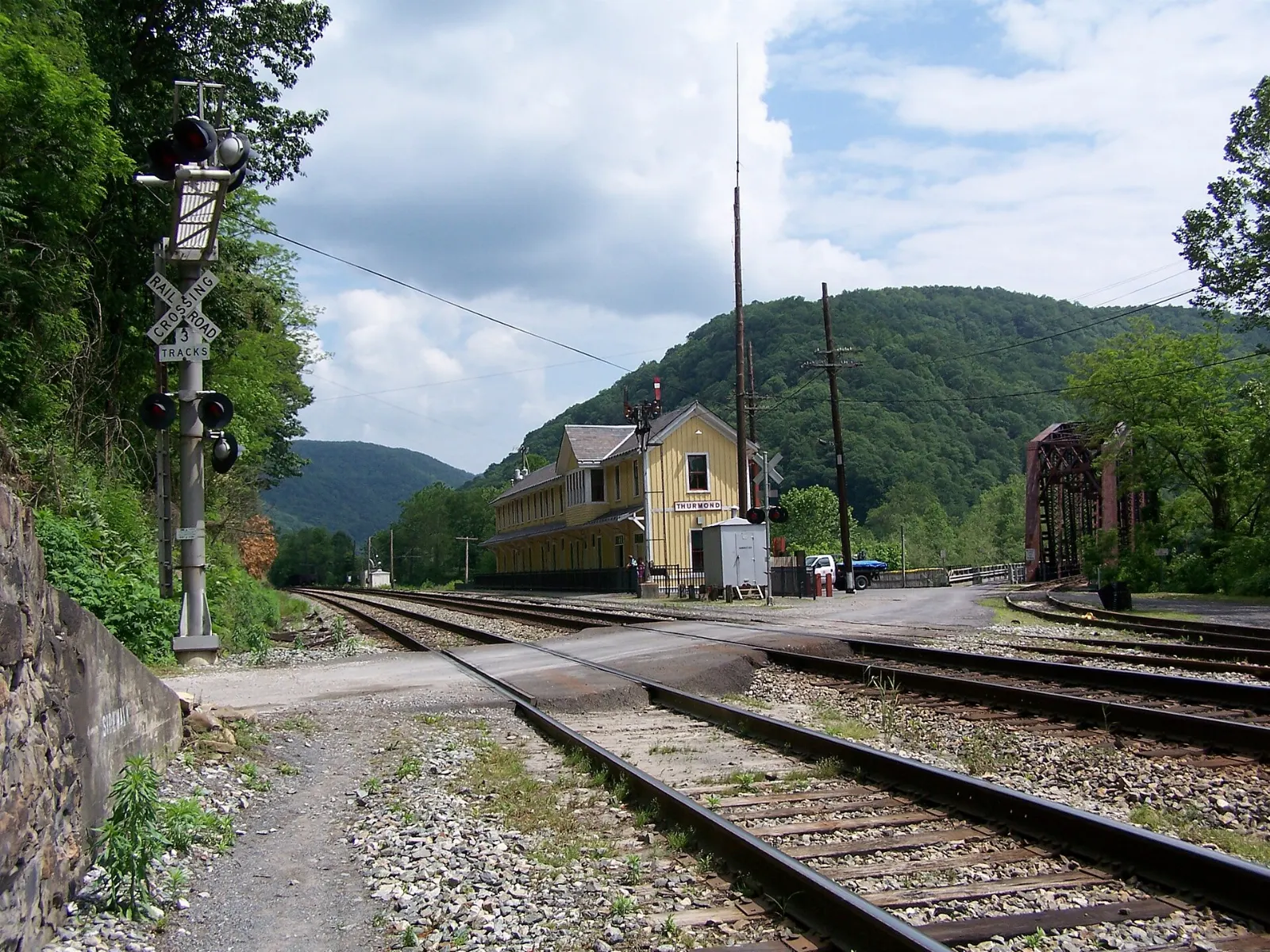 A restored railroad depot beside tracks and old brick buildings along a river, New River Gorge National Park, West Virginia