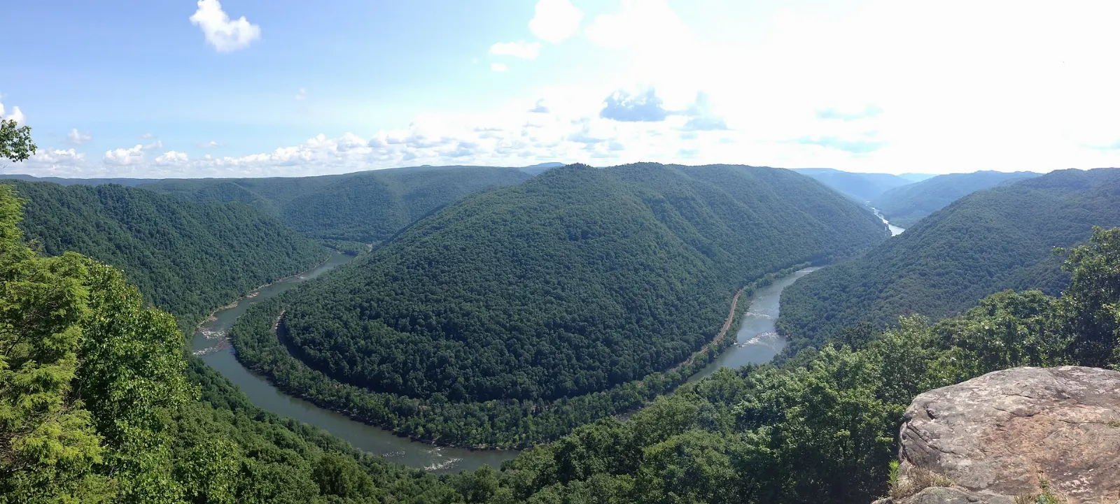 A wide view over a sweeping bend of a river through forested mountains, New River Gorge National Park, West Virginia