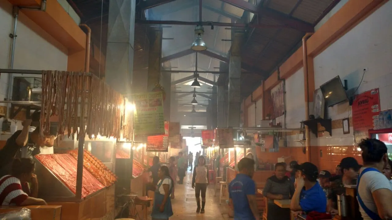 Grills and smoke inside a busy Oaxaca market aisle, Mexico