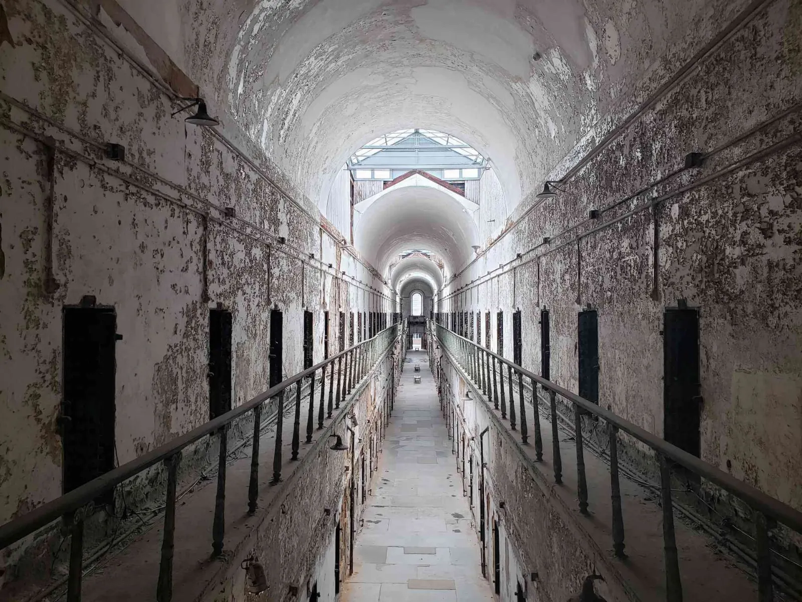 A long vaulted cellblock corridor with peeling walls at Eastern State Penitentiary, Philadelphia, Pennsylvania