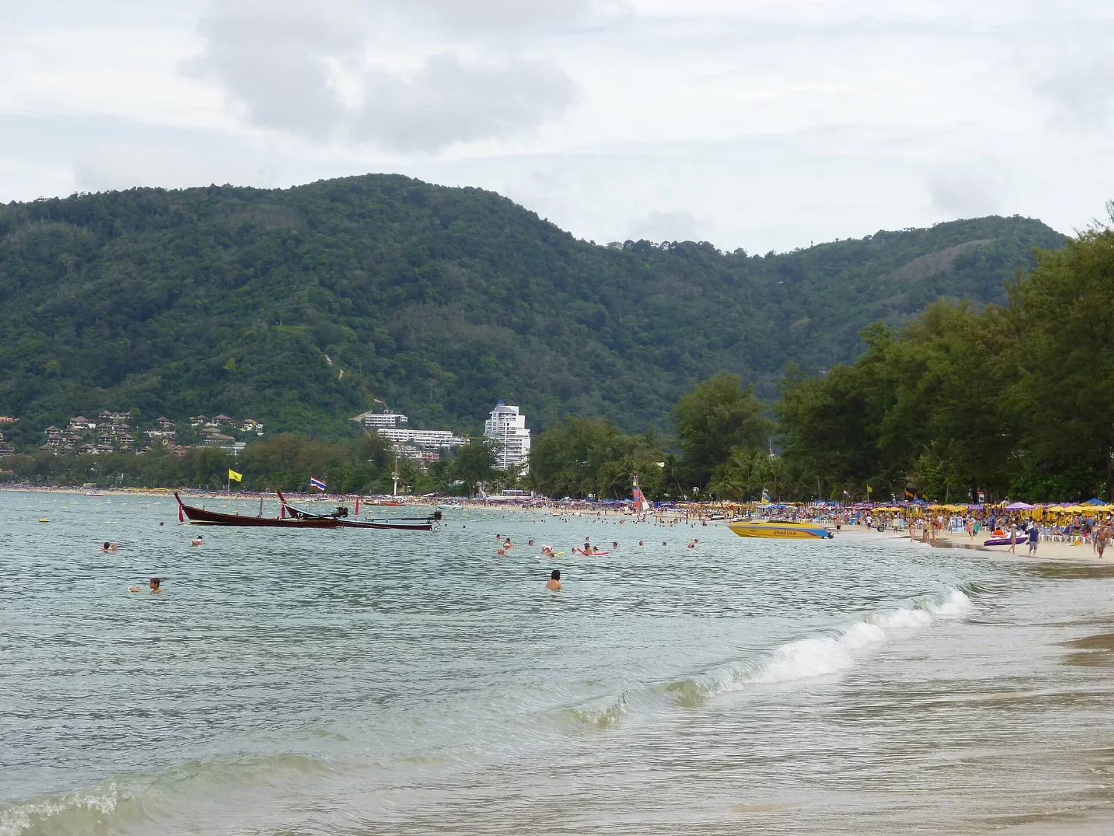 Long crescent of Patong Beach with swimmers and the town behind it, Phuket, Thailand