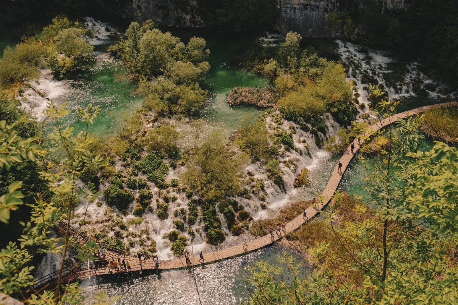 Wooden boardwalk crossing clear turquoise water in the canyon of the Lower Lakes, Plitvice Lakes National Park, Croatia