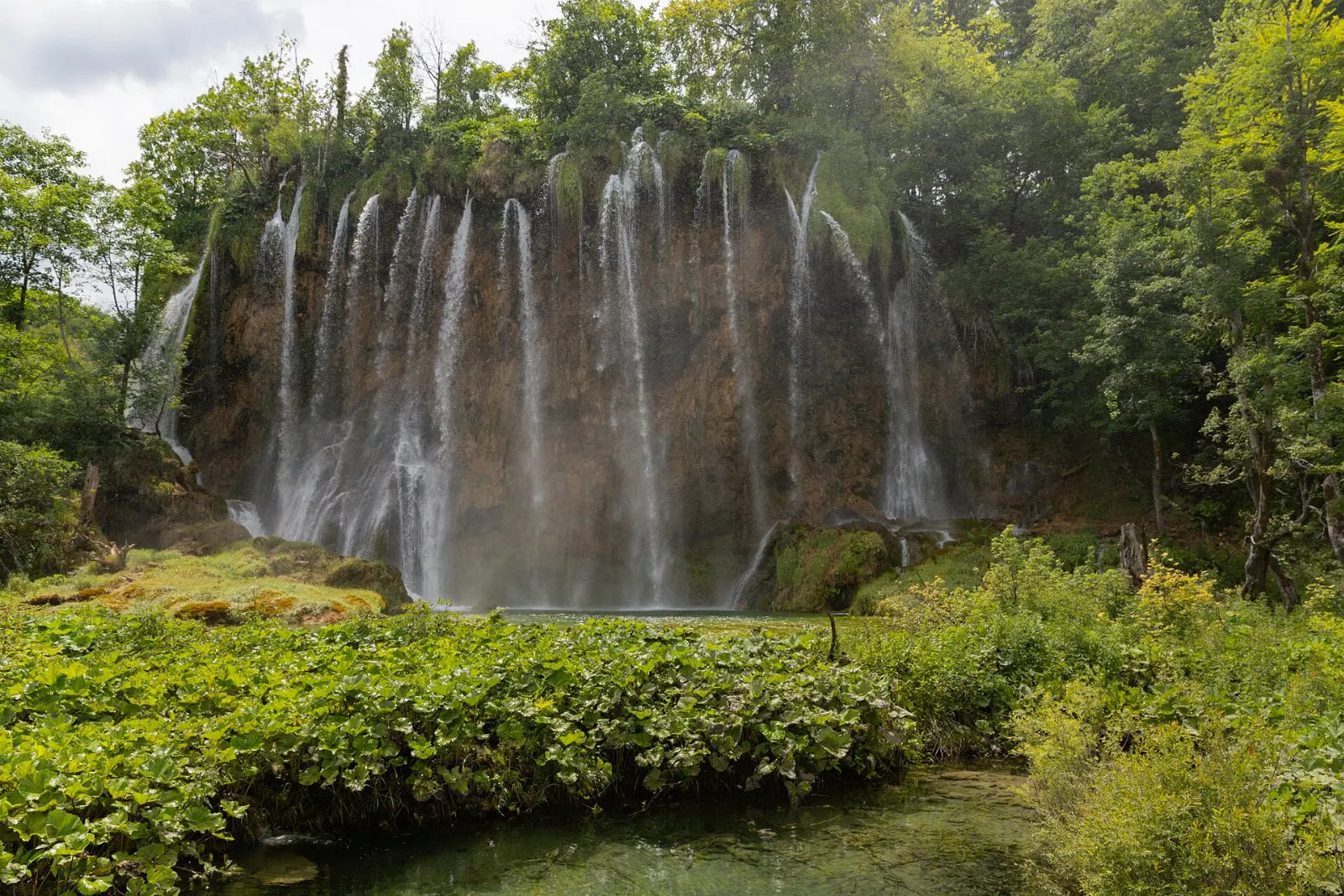 Broad white waterfall falling through forest in the Upper Lakes, Plitvice Lakes National Park, Croatia