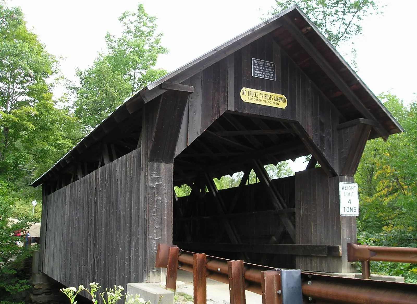 Red-roofed wooden covered bridge over a brook in the woods, Stowe, Vermont