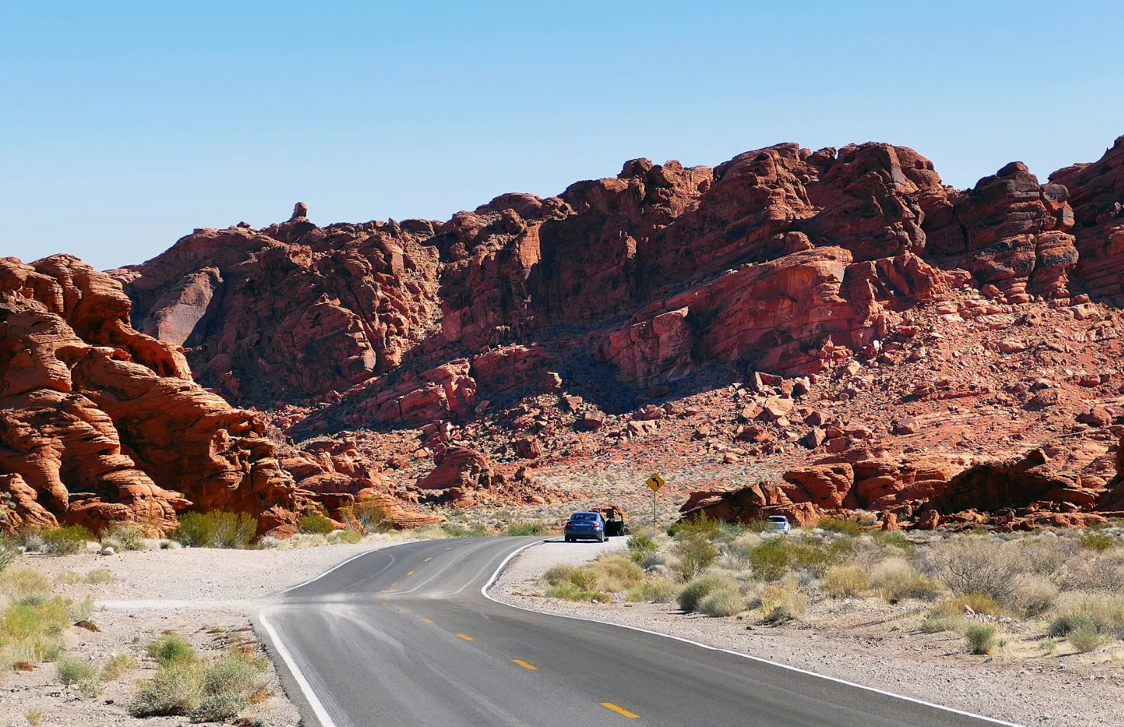 A paved road winding between red sandstone outcrops in the Mojave Desert, Valley of Fire State Park, Nevada
