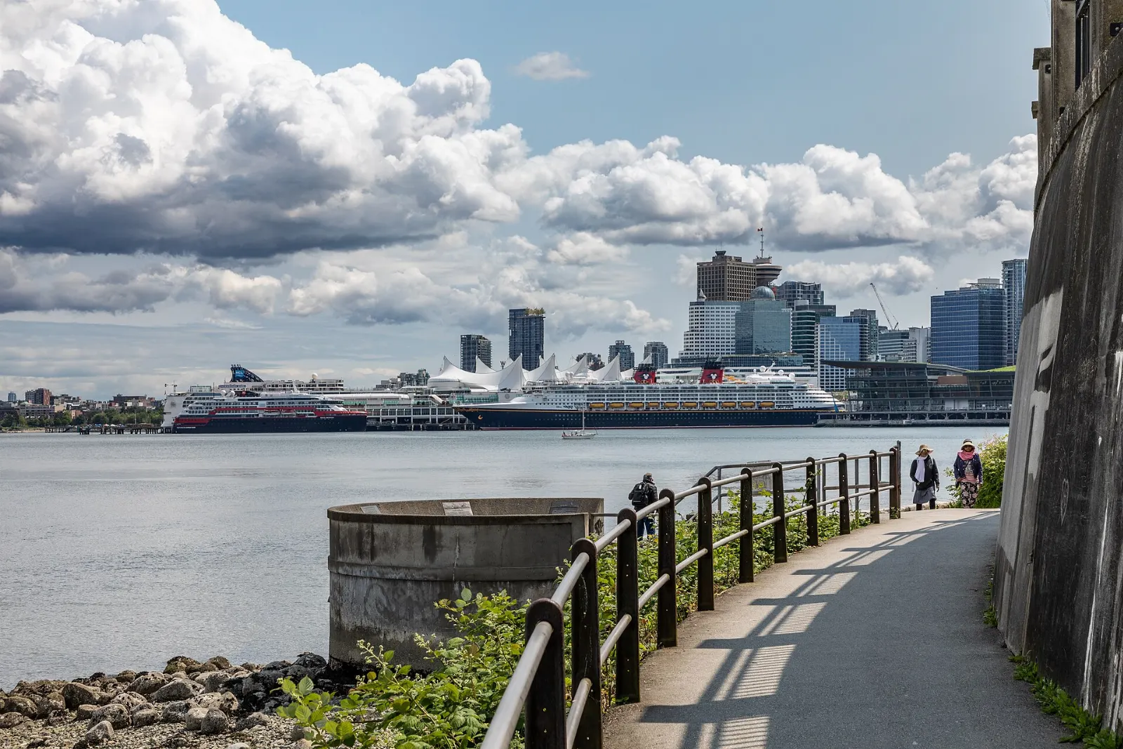 Walkers and cyclists on the Stanley Park seawall beside the ocean, Vancouver, Canada