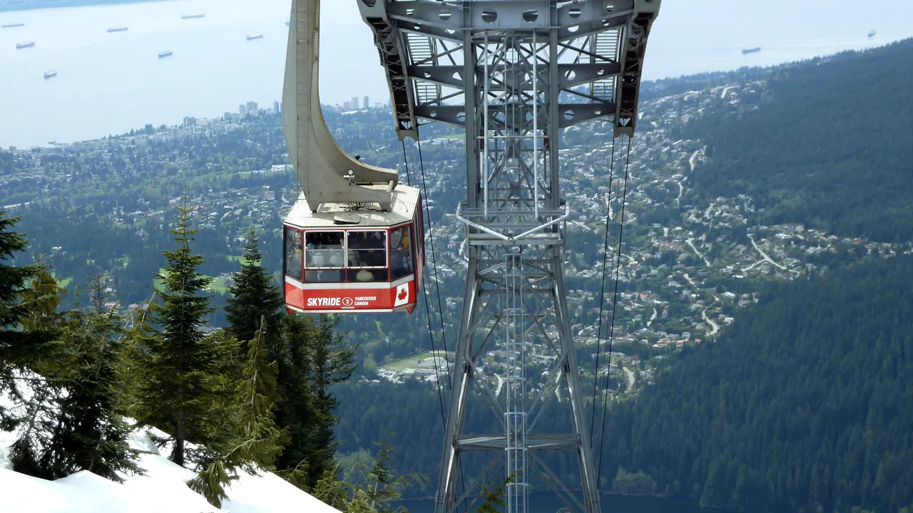 A red aerial tram climbing the forested slope of Grouse Mountain, Vancouver, Canada