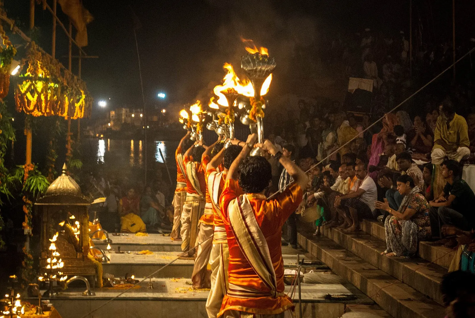 Priests holding tall brass lamps during the evening Ganga Aarti at Dashashwamedh Ghat, Varanasi, India
